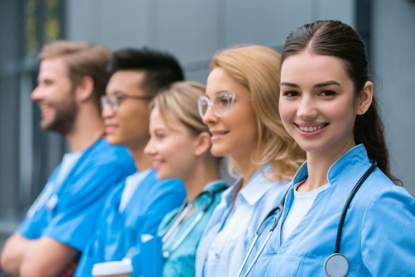 A group of nursing students standing in a row with one and smiling in an outdoor setting