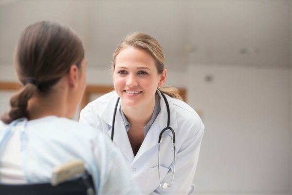Young female family nurse practitioner chatting with a patient in her office