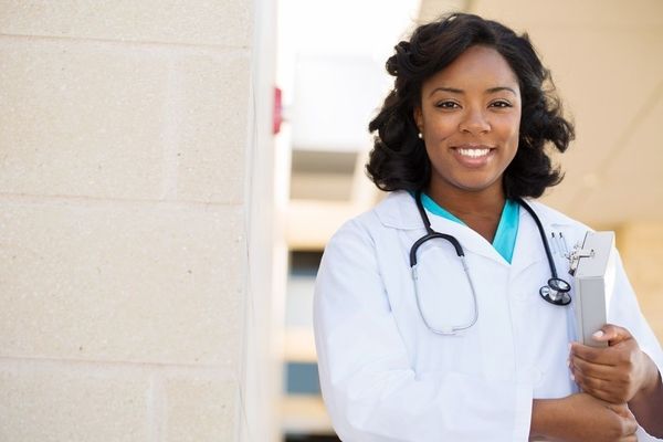 Female family nurse practitioner in a white lab coat smiling and looking confident