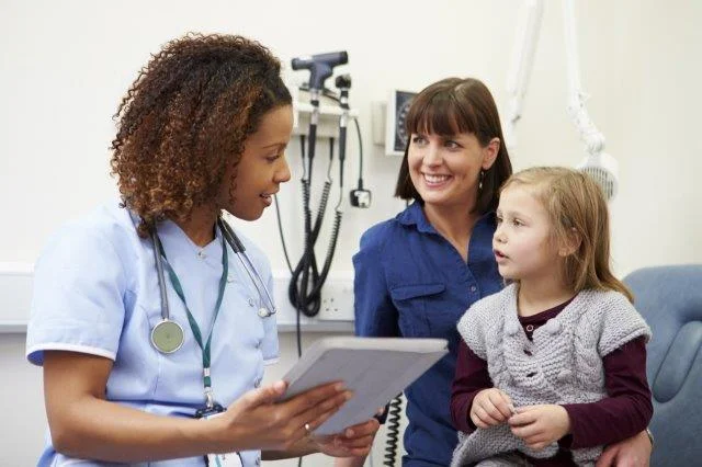 Nurse smiling at young patient and her mother