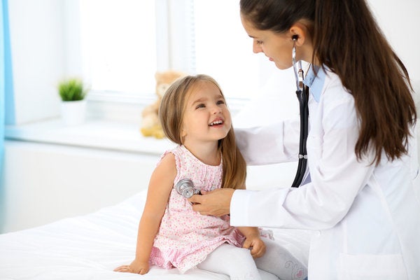 Family nurse practitioner using a stethoscope to listen to a young girl's hearbeat