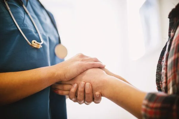 Close-up of a nurse holding the hands of a patient