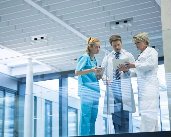 Two doctors and a nurse reviewing medical files in a hospital setting