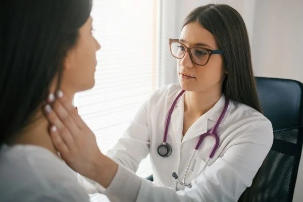 Young female family nurse practitioner examining a female patient with her hands placed on either side of the patient's neck