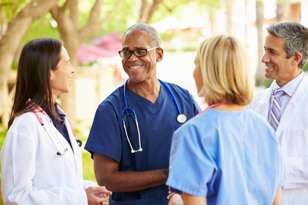 Mixed group of medical professionals laughing and chatting together outdoors