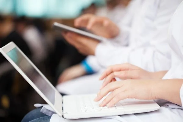 Close-up of a woman's hands typing on a laptop computer in class