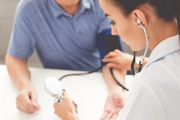 Female nurse practitioner performing blood pressure check on male patient