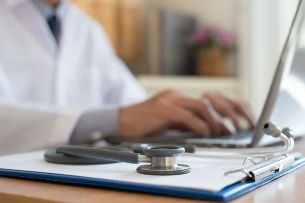 Close-up of a doctor's hands typing on a laptop computer