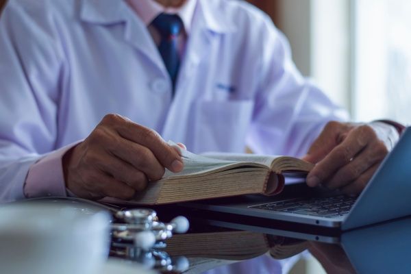 Close-up of male nurse practitioner in white lab coat reading a book