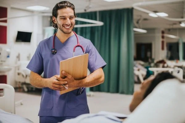 Smiling male nurse holding a clipboard and chatting with a patient