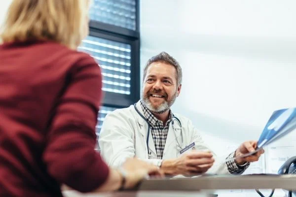 Smiling male nurse practitioner reviewing X-rays with a female patient in office setting