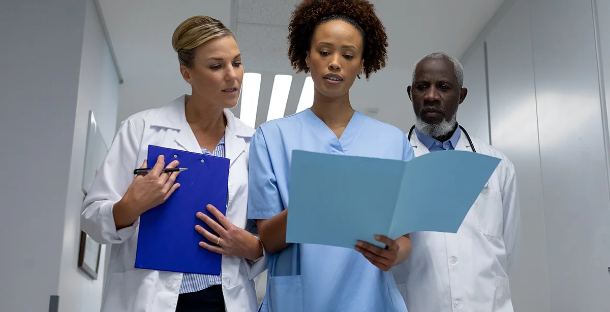 Family nurse practitioner walks with team of doctors reviewing patient data