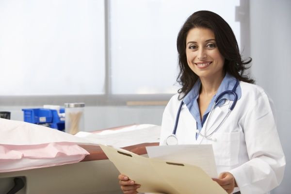 Smiling female nurse practitioner filing patient records in a private practice office