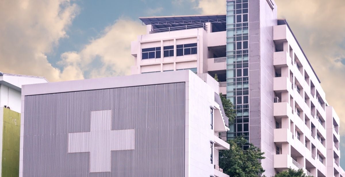 Hospital with a large cross on it against a cloudy sky background
