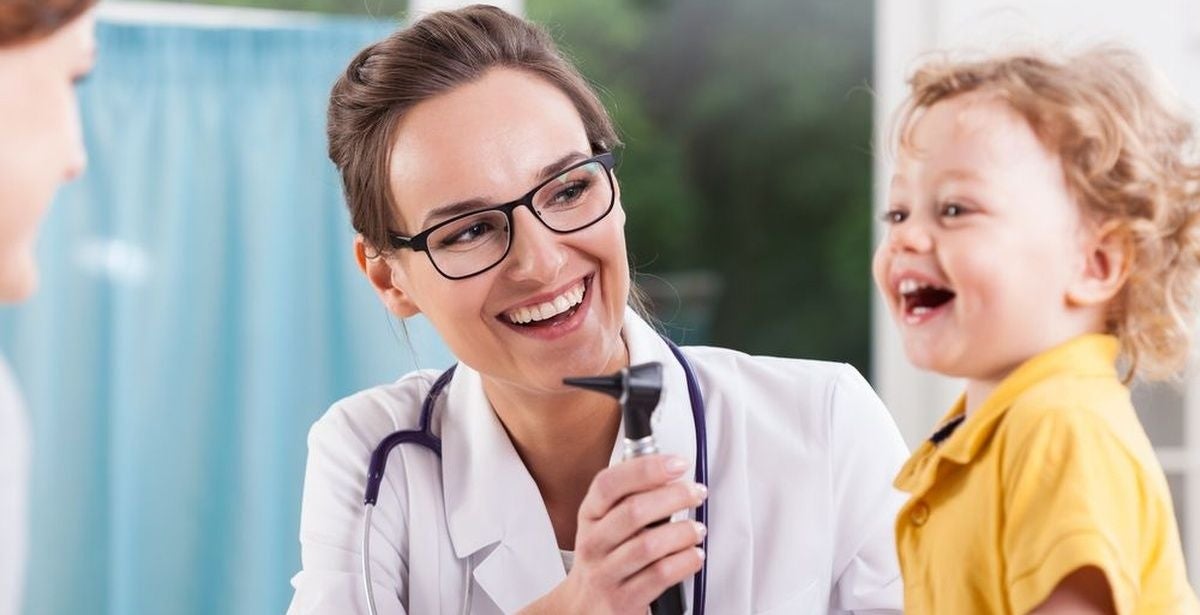 Female family nurse practitioner performing check-up on a smiling toddler