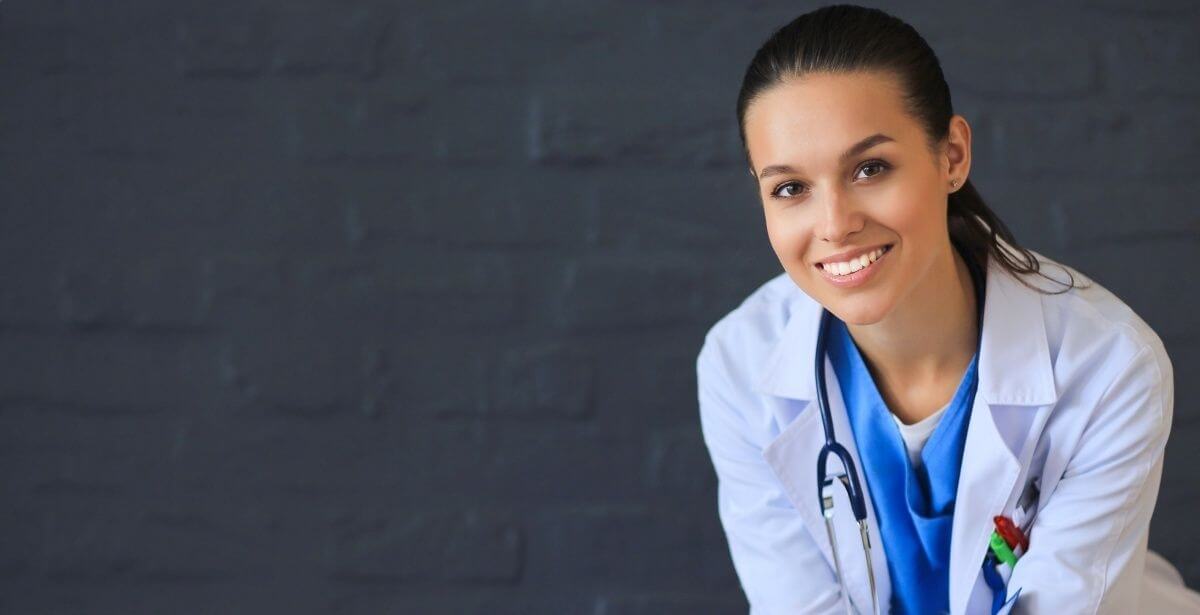 Smiling female nurse practitioner against dark grey background
