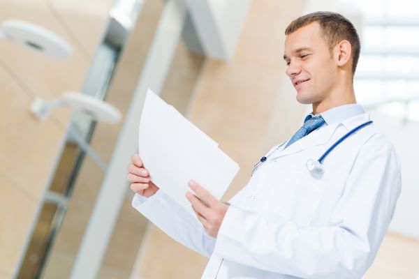 Male nurse practitioner in white lab coat reviewing medical files