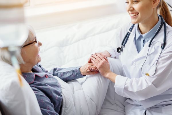 Female nurse practitioner clasping the hand of an elderly female patient
