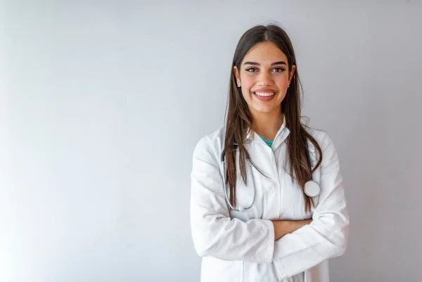 Smiling female nurse practitioner crossing her arms against a white background