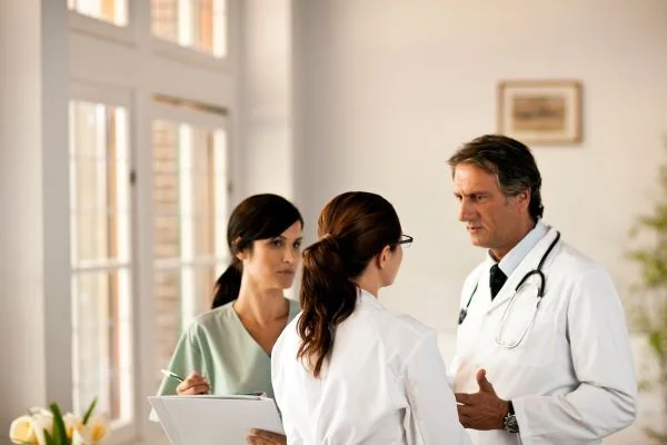 Two doctors and a nurse talking in a brightly lit room