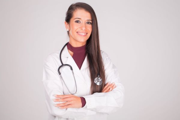 Smiling female nurse practitioner with crossed arms against a white background