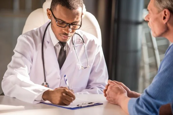 Male nurse practitioner writing a patient a prescription