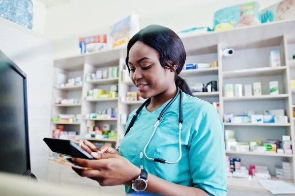 Female nurse in green scrubs behind the counter at a pharmacy