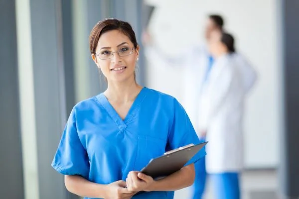 Smiling nurse wearing glasses and holding a clipboard