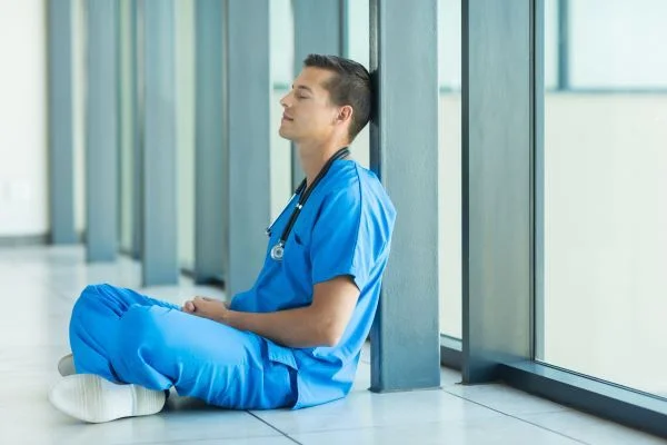 Male nurse sitting with crossed legs and performing breathing exercises