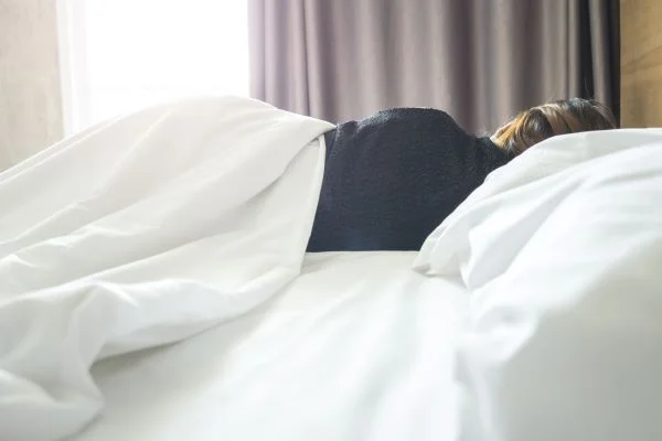 Woman lying in bed asleep with light pouring through the bedroom window