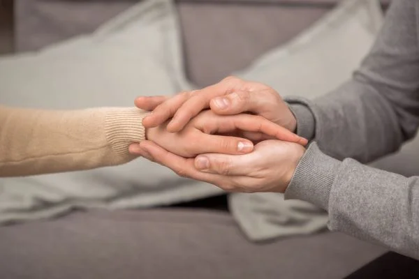 Close-up of a psychotherapist clasping the hand of her patient