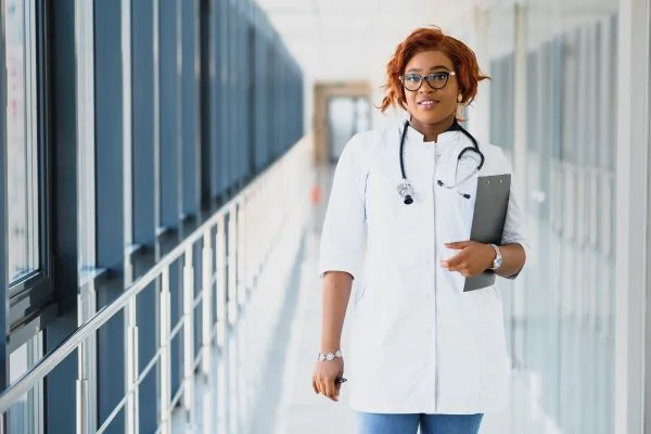 Family nurse practitioner in hospital corridor holding a clipboard