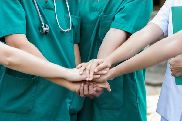 A group of nurses placing their hands together in a circle