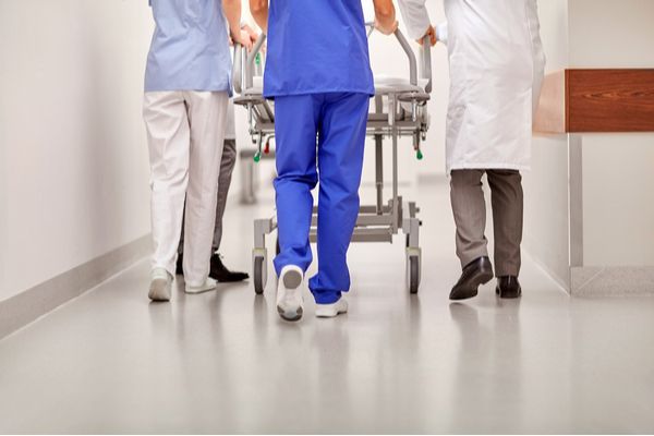 Healthcare workers pushing a hospital bed down a hospital corridor