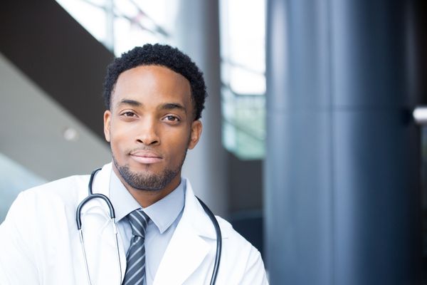 Male nurse practitioner in white coat looking confident