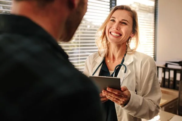 Smiling nurse practitioner talking to her male patient