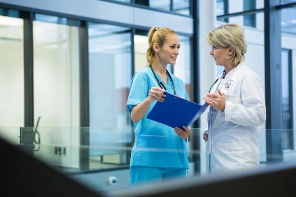 Female nurse practitioner discussing patient records with a young nurse